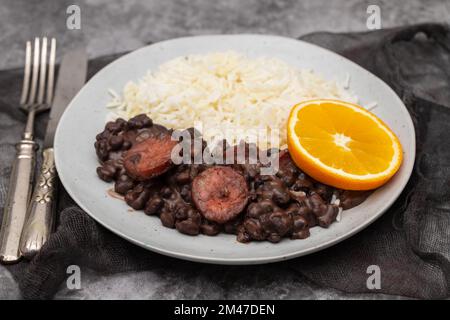 Fagioli tipici brasiliani con salsicce e riso Feijoada su piatto bianco Foto Stock
