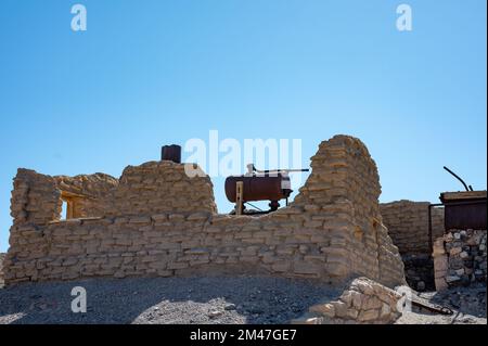 Resti di una vecchia casa nel deserto, solo un pezzo di muro e un deposito di metallo Foto Stock