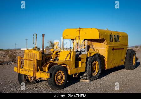 Trattore giallo che trasporta un rimorchio con un serbatoio di propano. Caterpillar serie DX10 1N 4x2. Viene abbandonato Foto Stock