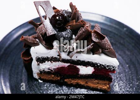 fetta di torta di foresta nera multistrato con crema di ciliegie e spugna di cioccolato Foto Stock