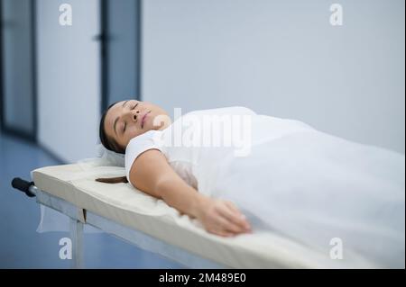 Una donna sdraiata su un gurney befre procedura diagnostica Foto Stock