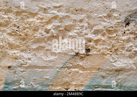 Muro di mattoni vecchio e danneggiato con imbiancatura e sfumature di vernice spray colla. Foto Stock
