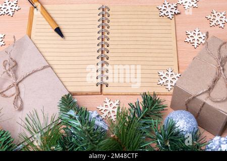 Taccuino vuoto aperto, diario, regali in scatole fatte a mano, rami di abete e fiocchi di neve in legno. Concetto della lista dei regali. Concetto di pianificazione del nuovo anno. Eco-friendly st Foto Stock