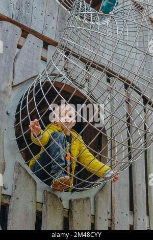 Un bambino sale su una griglia alpina in un parco giochi in una calda giornata estiva. parco giochi per bambini in un parco pubblico, intrattenimento e svago Foto Stock