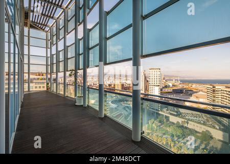 Ampia e lunga terrazza in alto edificio con recinzione e tetto in travi metalliche di vetro resistente agli urti protetto dalla luce diretta del sole Foto Stock