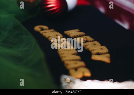 Parole di pan di zenzero buon Natale sul vecchio tavolo nero con decorazioni natalizie Foto Stock