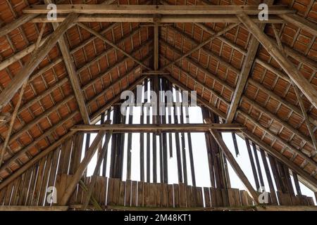 Interno di un vecchio fienile con costruzione di tetto e fatiscente timpano Foto Stock