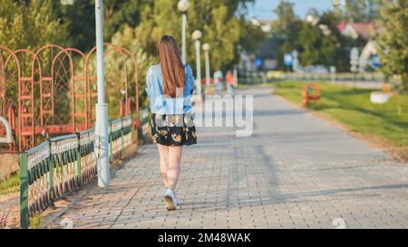 Una ragazza solitaria cammina lungo il lungomare della città. Foto Stock