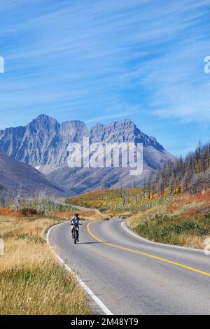 Ciclisti in mountain bike lungo una strada poco affollata nelle Montagne Rocciose canadesi. Waterton Lakes National Park, Alberta, Canada Foto Stock