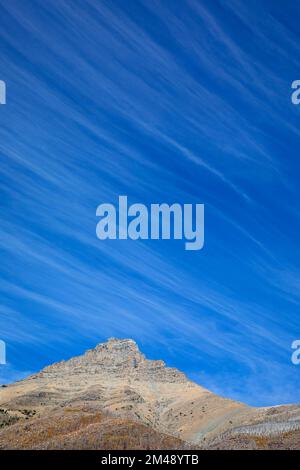 Nuvole di Cirrus nel cielo azzurro luminoso sopra la vetta della montagna nel Wateron Lakes National Park, Alberta, Canada Foto Stock