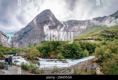 Il fiume Briksdalsselva con il ponte pedonale e il Briksdalsbreen (il ghiacciaio) sulla sinistra, nel Parco Nazionale di Jostedalsbreen, Norvegia. Foto Stock