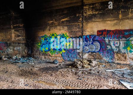 Muro graffiti e volate ribaltando all'interno di un tunnel di strada abbandonato. Foto Stock