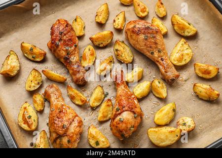 Foglio da forno con gustose patate e cosce di pollo al forno, primo piano Foto Stock