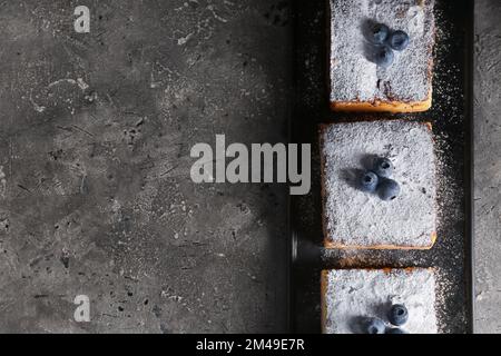 Torta al formaggio con mirtilli su un tavolo di grunge scuro Foto Stock