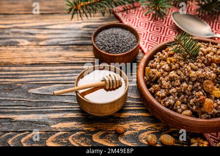 Ciotola di Kutya con ramo di Natale e ingredienti su sfondo di legno scuro Foto Stock