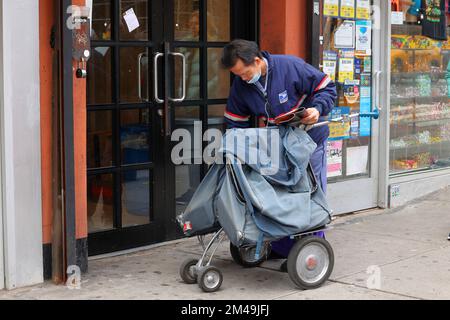 Un corriere di lettere USPS cinese-americano con un carrello postale a mano a New York City. Foto Stock