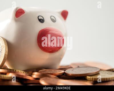 La banca del piggy sta sulle monete metalliche. Un mucchio di centesimi di euro e una banca del piggy. Primo piano. Foto Stock