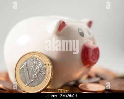 La banca del piggy sta sulle monete metalliche. Un mucchio di centesimi di euro e una banca del piggy. Primo piano. Foto Stock