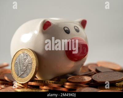 La banca del piggy sta sulle monete metalliche. Un mucchio di centesimi di euro e una banca del piggy. Primo piano. Foto Stock