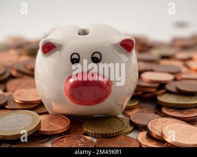 La banca del piggy sta sulle monete metalliche. Un mucchio di centesimi di euro e una banca del piggy. Primo piano. Foto Stock