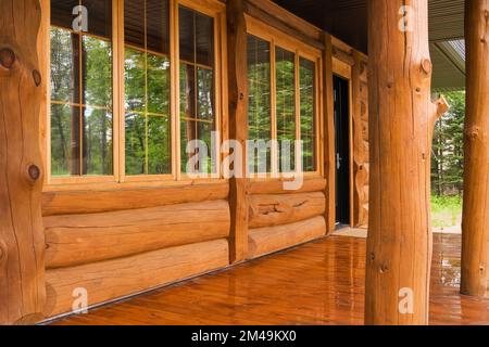 Facciata rustica casa in legno con finestre panoramiche in vetro e veranda. Foto Stock