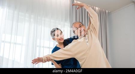 L'anziano ama allenarsi con il fisioterapista per le braccia distese a casa Foto Stock