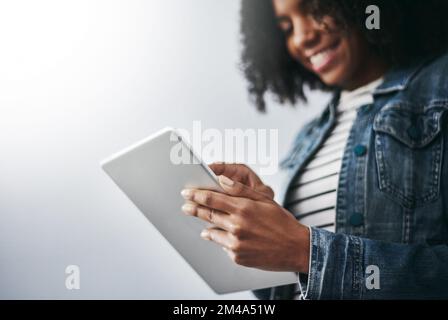 Connessione con il mondo. Studio di una giovane donna attraente utilizzando il suo tablet digitale su uno sfondo grigio. Foto Stock