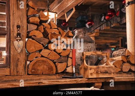 Legna da ardere e utensili sulla scrivania nella cabina di legno con palle di Natale appese al soffitto, Austria Foto Stock