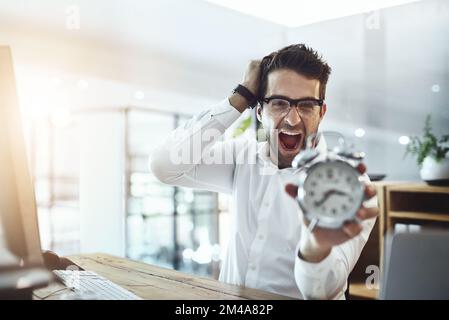 Tempi esauriti. Ritratto di un giovane uomo d'affari che guarda stressato mentre tiene un orologio in un ufficio. Foto Stock