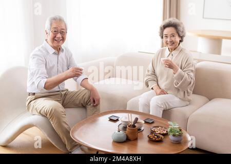 Allegro coppia cinese anziana bere tè a casa Foto Stock