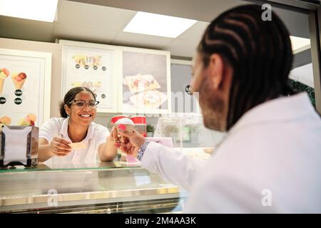 Lavoratore africano che serve una terrina di gelato ad un cliente Foto Stock