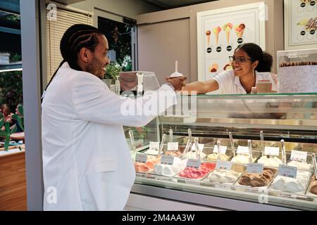 Lavoratrice africana che serve un cliente in una gelateria Foto Stock