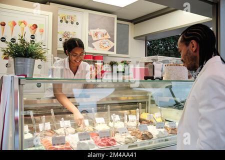 Lavoratore che serve un cliente in una gelateria Foto Stock