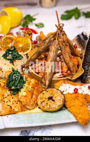 una serie di piatti di pesce diversi su un piatto bianco. Foto Stock
