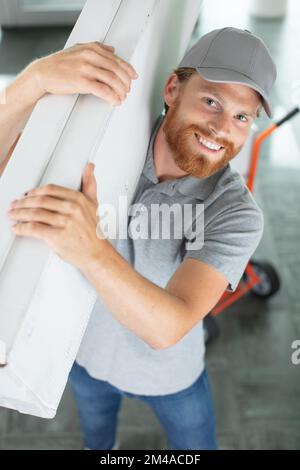 carpentiere che tiene tavole in una nuova casa Foto Stock