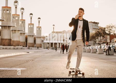 Uomo elegante che pattina mentre parla con il cellulare Foto Stock