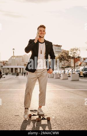 Uomo che pattina mentre parla con il cellulare Foto Stock