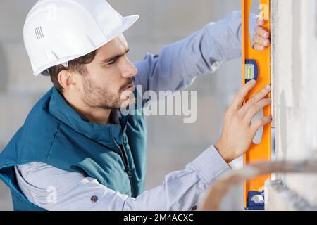 lavoratore che utilizza il livello della linea laser Foto Stock