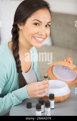 la donna sente l'odore di olio aromatico e usa il diffusore Foto Stock