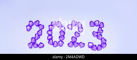 Iscrizione di Capodanno 2023 da cuori di vetro su sfondo viola. Colore Pantone 2023. Idea e creatività. San Valentino. Natale con i propri cari. Orizzontalmente, banner. Foto di alta qualità Foto Stock