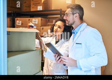 Il marchio più recente è arrivato. una giovane donna e una donna matura che usano un tablet digitale mentre fanno l'inventario in una farmacia. Foto Stock