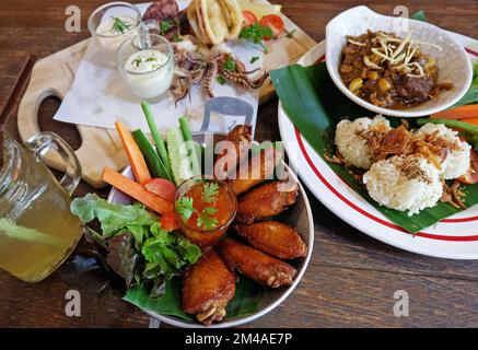 Riso appiccicoso fritto servito con curry della Thailandia settentrionale, ali di pollo e calamari fritti in pastella Foto Stock