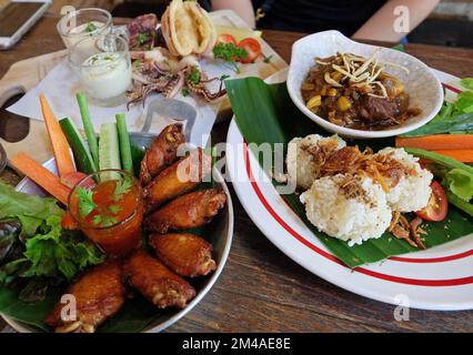 Riso appiccicoso fritto servito con curry della Thailandia settentrionale, ali di pollo e calamari fritti in pastella Foto Stock