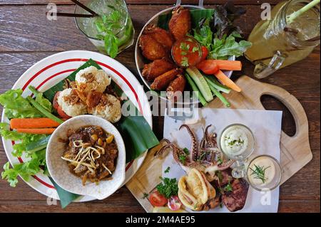 Riso appiccicoso fritto servito con curry della Thailandia settentrionale, ali di pollo e calamari fritti in pastella Foto Stock