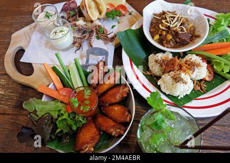 Riso appiccicoso fritto servito con curry della Thailandia settentrionale, ali di pollo e calamari fritti in pastella Foto Stock