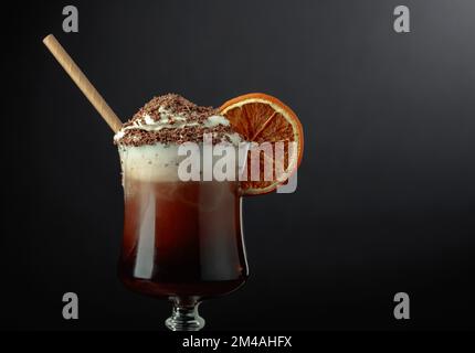 Cocktail al cioccolato con panna montata cosparsa di gocce di cioccolato e guarnita con una fetta di arancia secca. Spazio di copia. Foto Stock