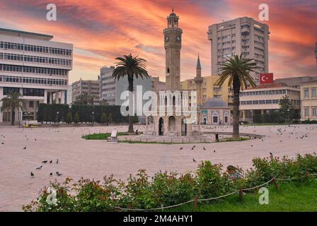 Vista della via Konak Square con la vecchia torre dell'orologio (Saat Kulesi) al tramonto. Fu costruito nel 1901 e accettato come simbolo ufficiale della città di Smirne, in Turchia. Foto Stock