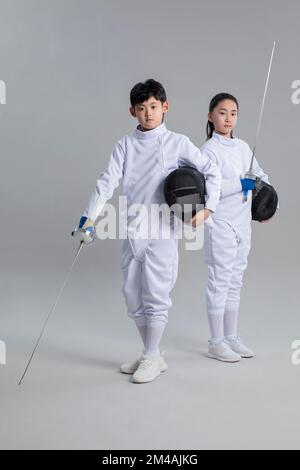 Ragazza cinese carina e ragazzo in tuta di scherma Foto Stock