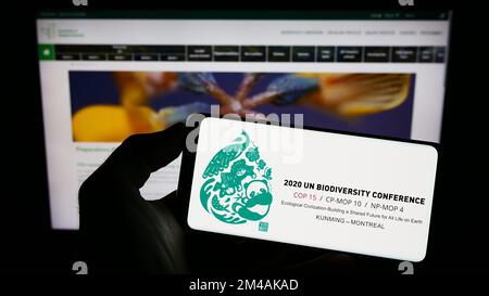 Persona che tiene il cellulare con il logo della conferenza sulla biodiversità CBD COP 15 a Montreal sullo schermo di fronte alla pagina web. Messa a fuoco sul display del telefono. Foto Stock