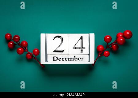 Data della vigilia di Natale su cubo di legno bianco Calendario, 24 dicembre, con decorazioni di Natale e bacche rosse su sfondo verde Natale cartolina di Natale Cristo Foto Stock